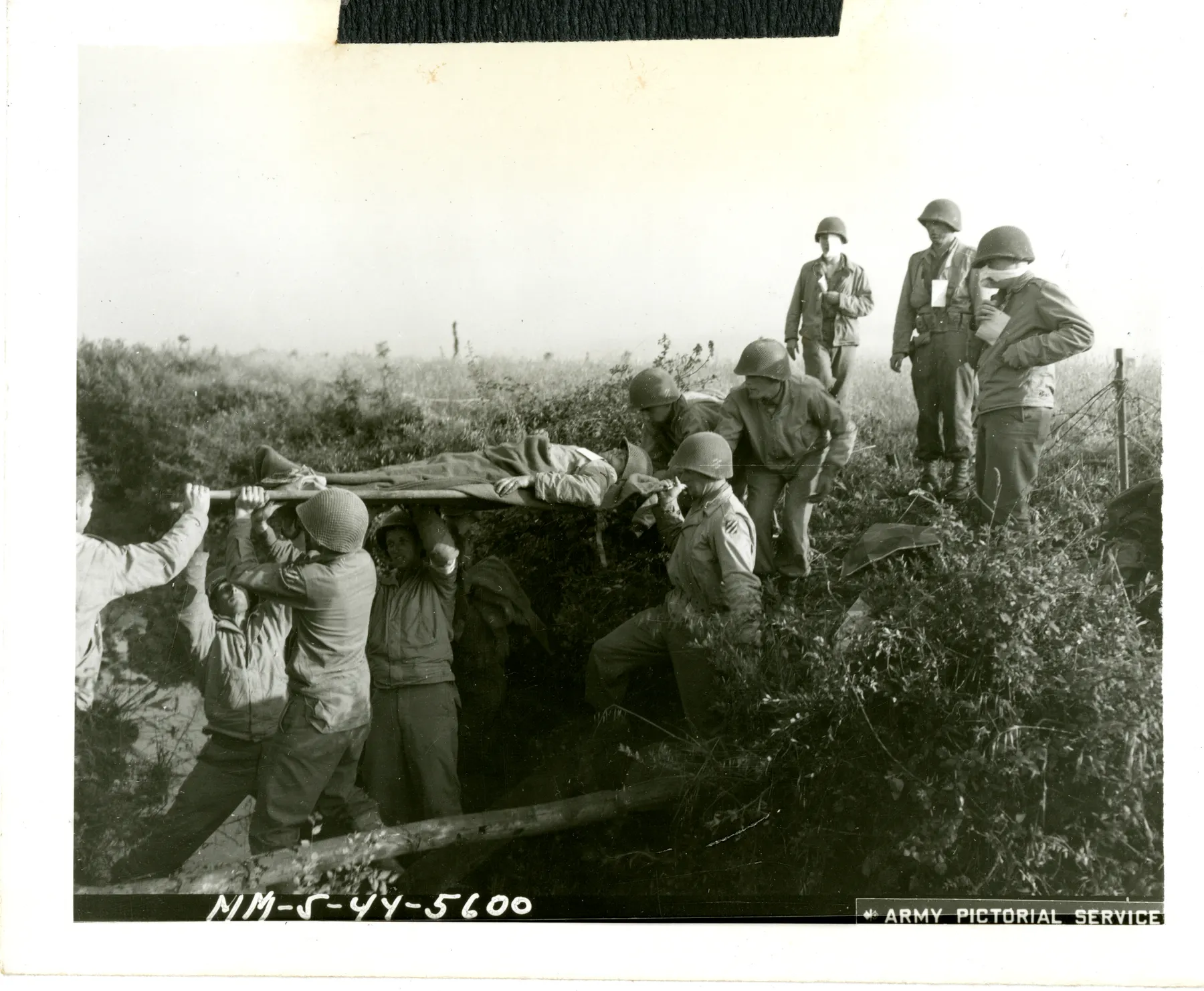 American infantry medics carrying a wounded soldier on a stretcher through scrub near Cisterna, Italy, 1944