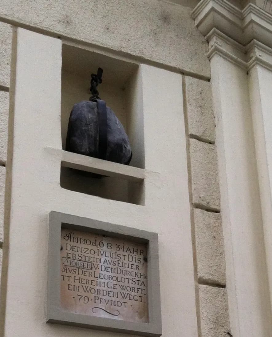 A stone cannonball set into a niche on a building facade in Vienna's Sterngasse, with a plaque below